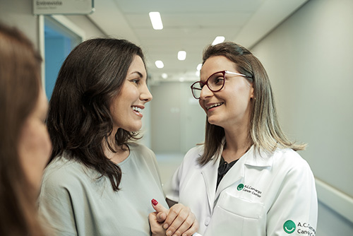 Duas mulheres brancas rindo e conversando dentro do Hospital.