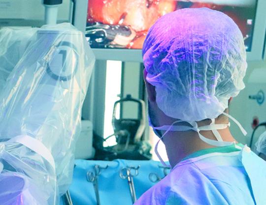 Um médico paramentado em um centro cirúrgico com equipamento de cirurgia robótica