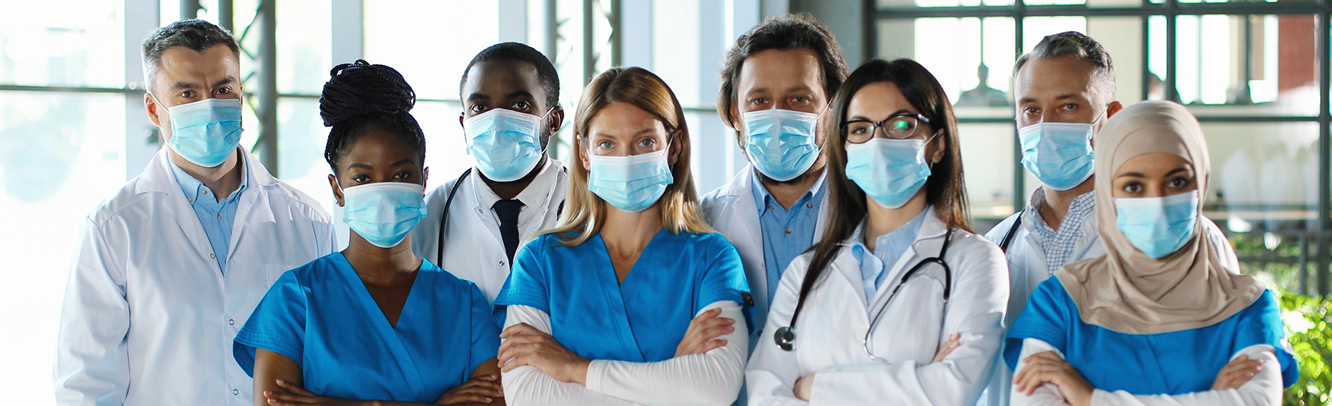 Uma equipe de profissionais de saúde de diferentes nacionalidades, todos com máscara e avental de médico